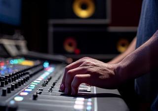 Sound engineer working on an audio mixing board in a studio